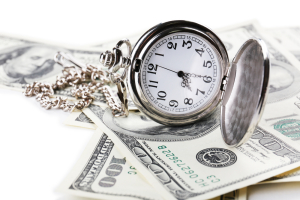 Silver pocket watch lies open on $100 bills close-up. Time is money concept.