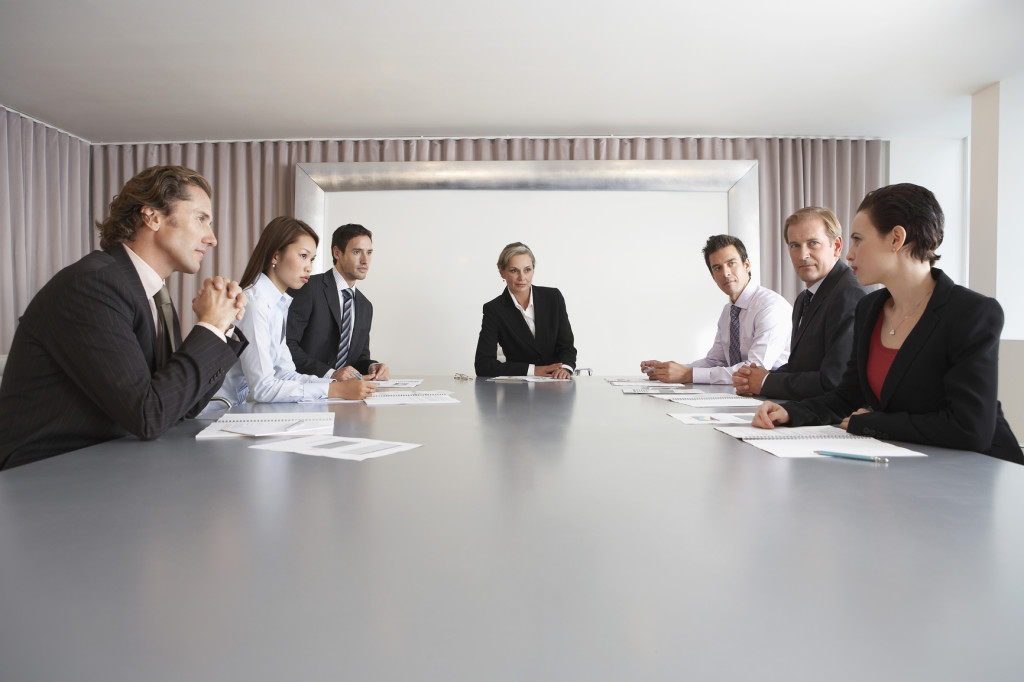 Businesspeople in conference room during meeting with leader at the head of the table.