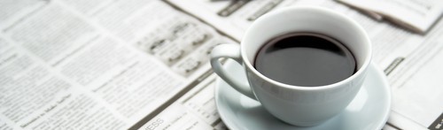 Coffee cup and recent news editions.